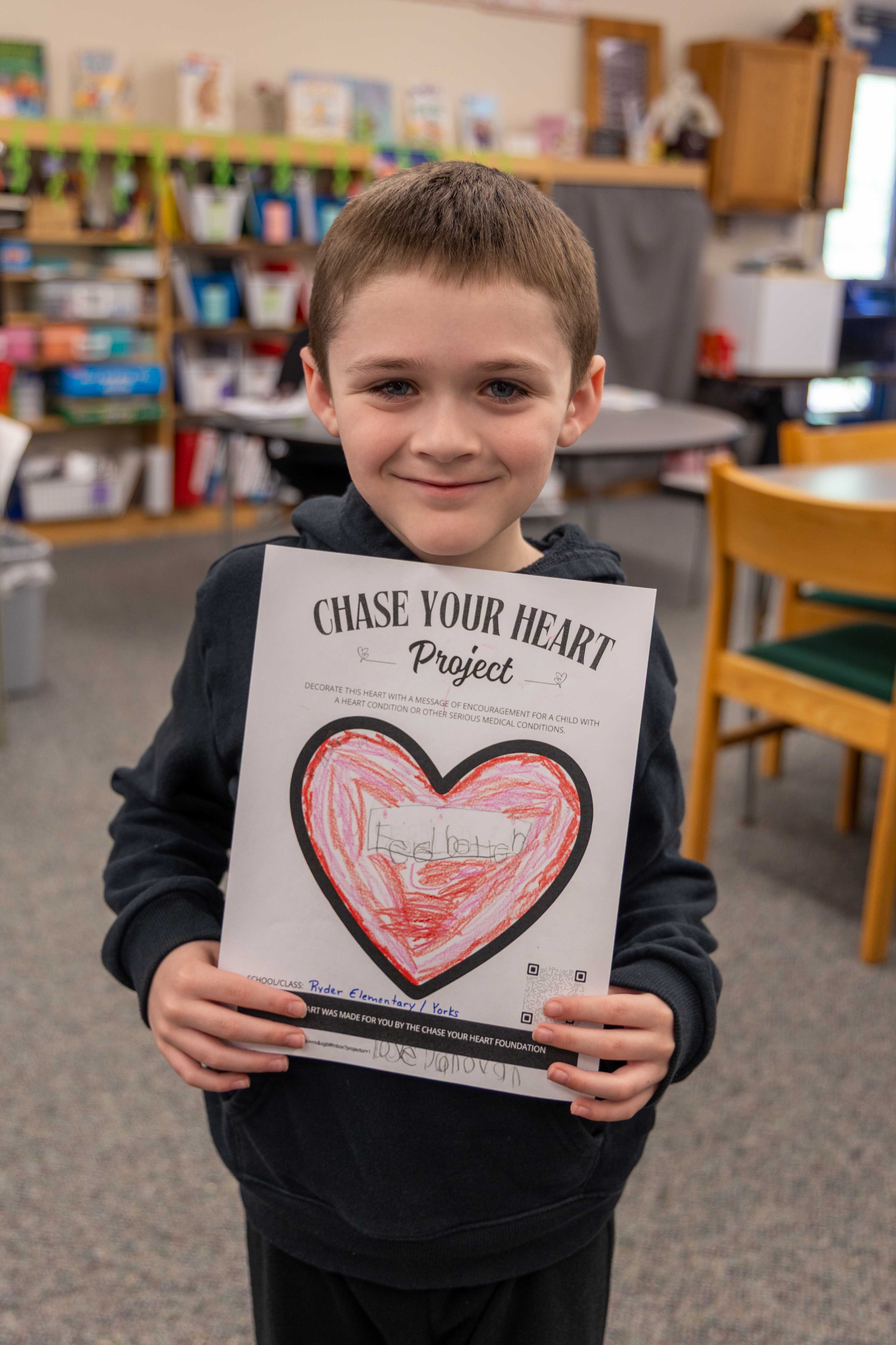 A young student holds his heart design.